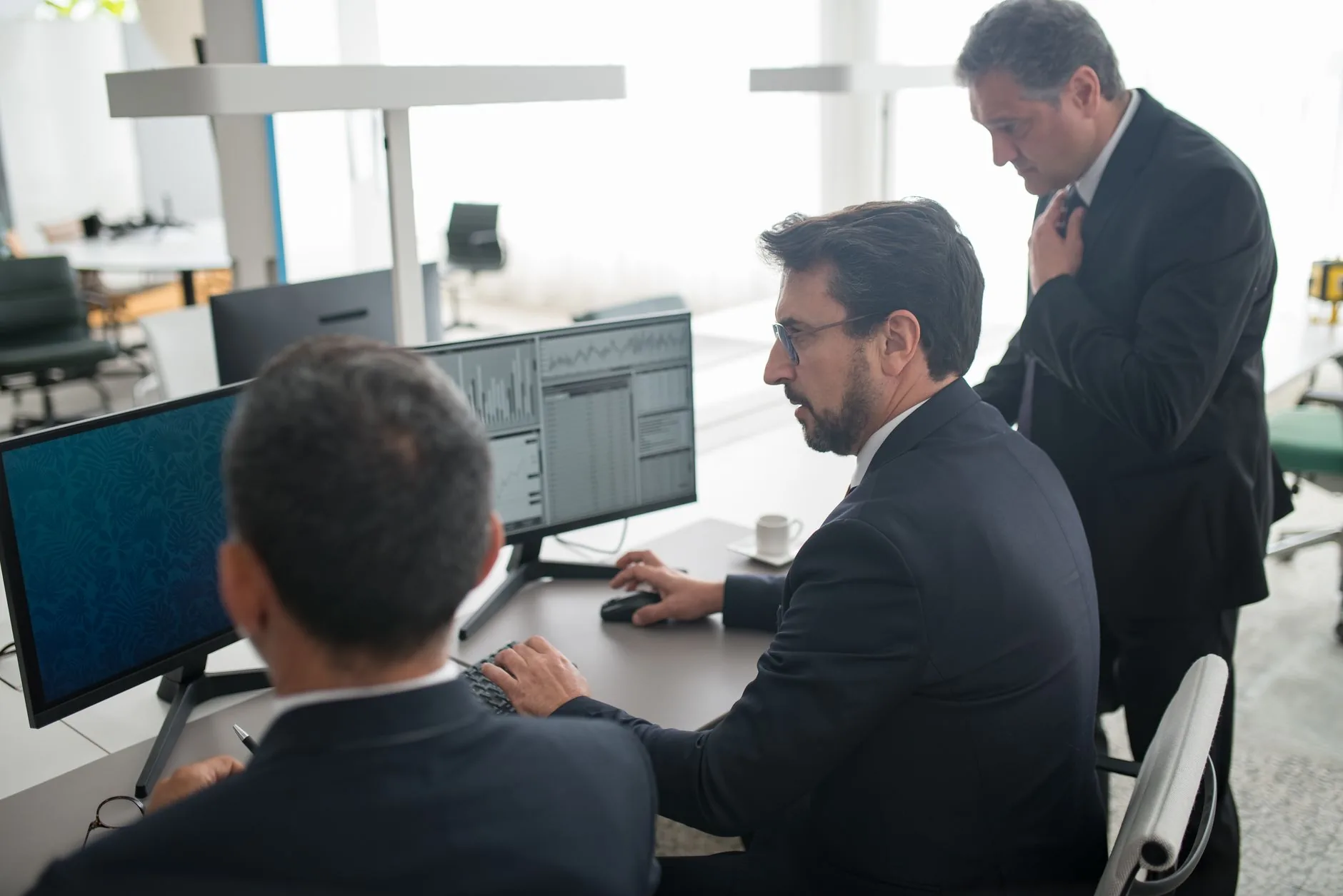 Analistas de SOC monitorando painéis de alertas e gráficos de detecção de ameaças em uma central de operações de segurança