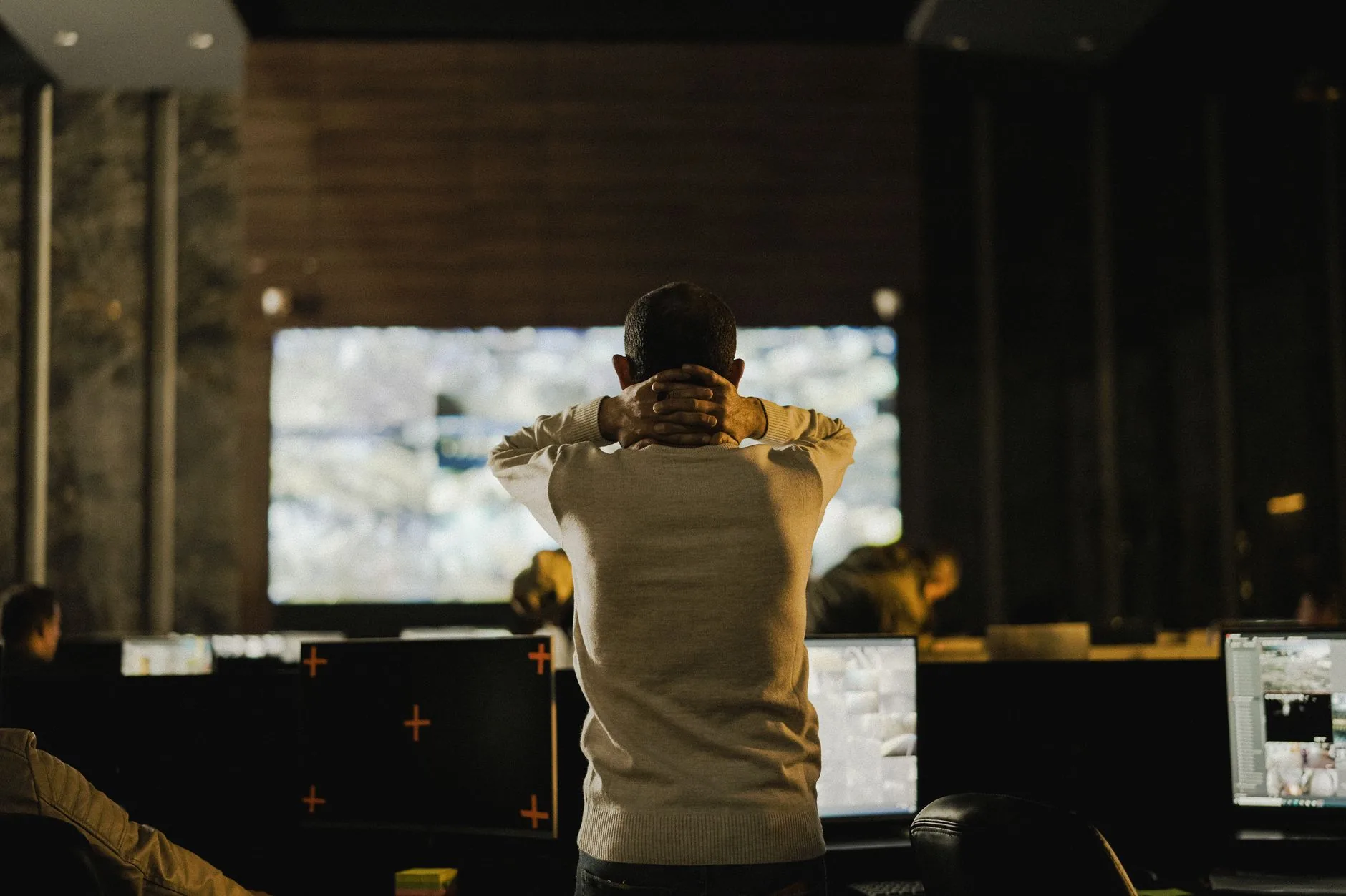 Analista de SOC trabalhando em uma sala escura com múltiplos monitores exibindo alertas de segurança e dashboards de análise